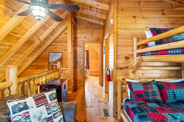 bedroom with vaulted ceiling with beams, wood ceiling, wooden walls, and hardwood / wood-style floors