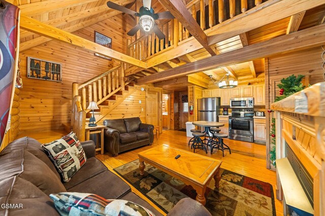 living room with light hardwood / wood-style flooring, wooden ceiling, beamed ceiling, and wood walls