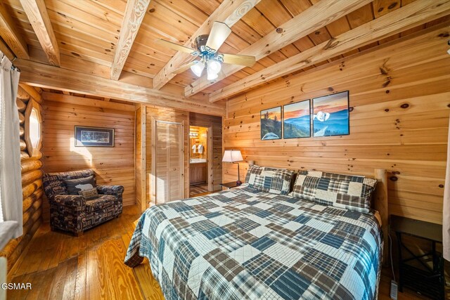 bedroom with wooden walls, beamed ceiling, hardwood / wood-style flooring, ceiling fan, and wooden ceiling