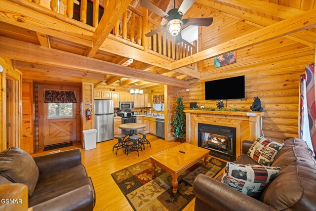 living room featuring sink, light hardwood / wood-style flooring, ceiling fan, rustic walls, and a high ceiling