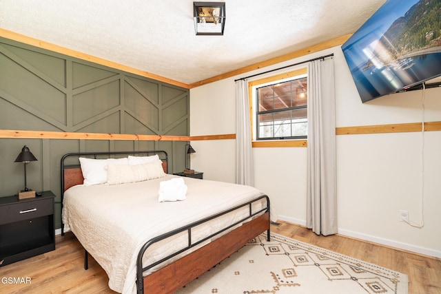 bedroom with light wood-type flooring and a textured ceiling