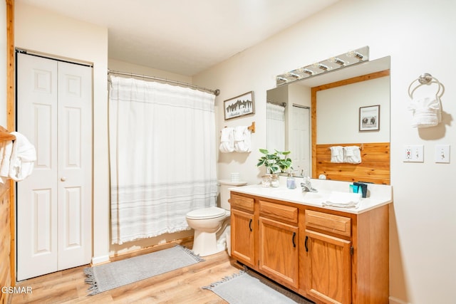 bathroom with wooden walls, toilet, vanity, and hardwood / wood-style flooring