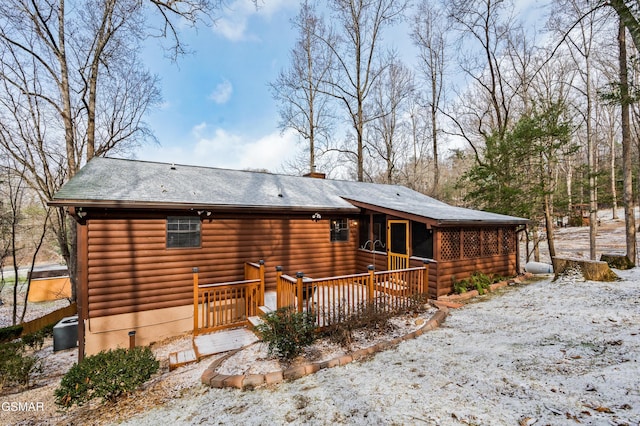 snow covered rear of property with a deck