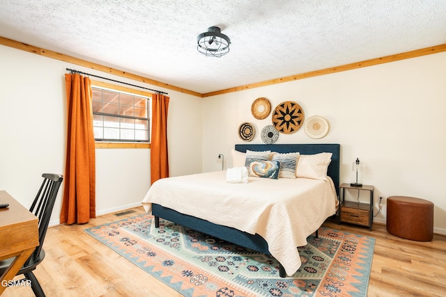 bedroom featuring hardwood / wood-style floors, a textured ceiling, and crown molding