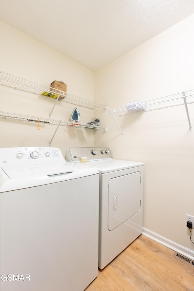 laundry area featuring washer and dryer and light hardwood / wood-style flooring