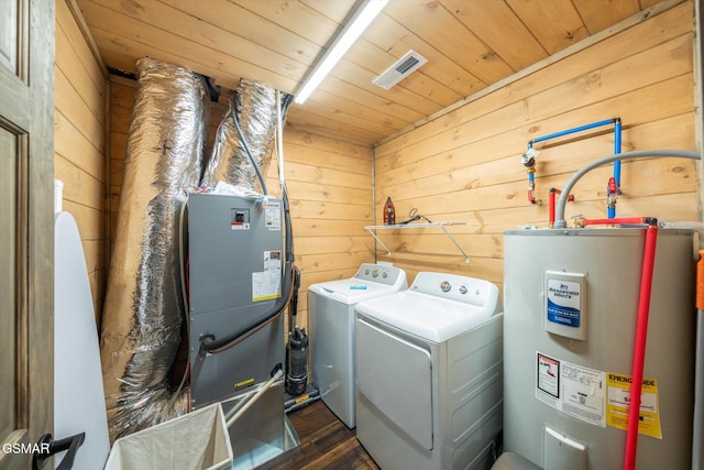 laundry room with water heater, wooden ceiling, washing machine and clothes dryer, and wood walls