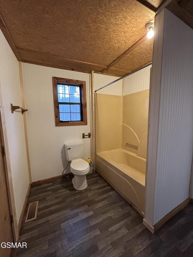 bathroom with toilet, bathtub / shower combination, hardwood / wood-style floors, and wood walls