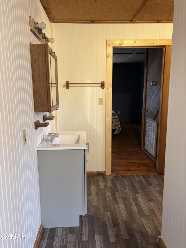 bathroom featuring vanity, wooden walls, and hardwood / wood-style floors