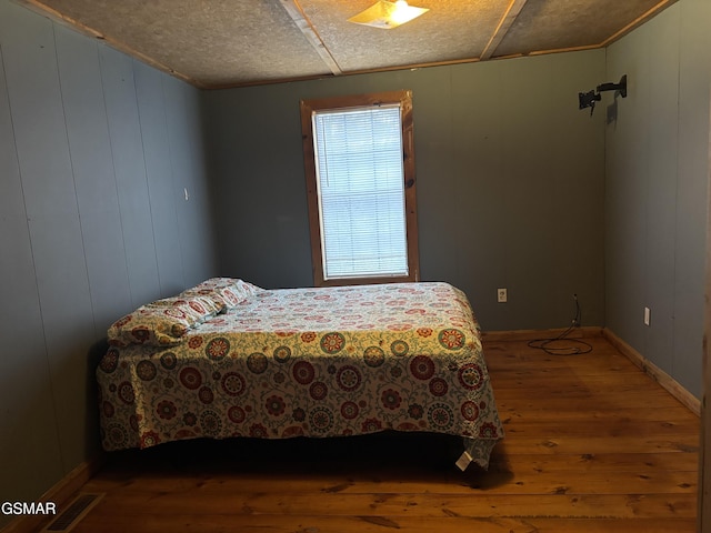 bedroom featuring hardwood / wood-style flooring and wood walls