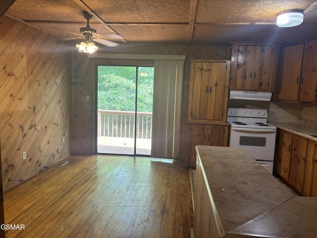 kitchen with ceiling fan, white electric range, wooden walls, and hardwood / wood-style floors