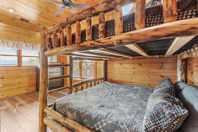 bedroom with wooden ceiling, wood walls, and multiple windows