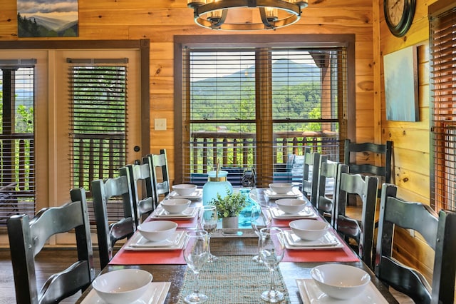 dining space with an inviting chandelier, wooden walls, and plenty of natural light
