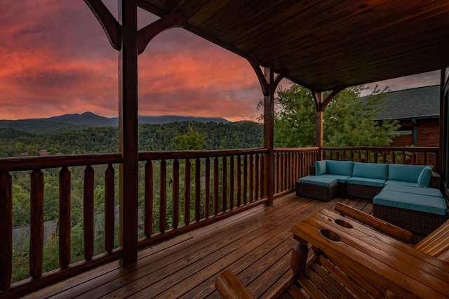 wooden deck with an outdoor hangout area, a mountain view, and a view of trees