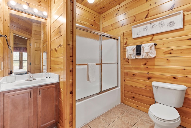 bathroom with wood walls, combined bath / shower with glass door, toilet, tile patterned floors, and vanity
