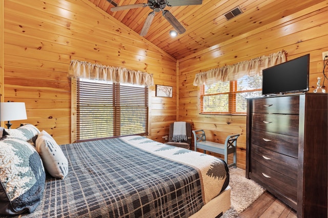 bedroom with wooden ceiling, wooden walls, wood finished floors, lofted ceiling, and visible vents