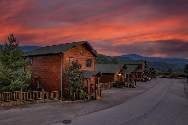 view of front of house featuring driveway, a mountain view, and fence