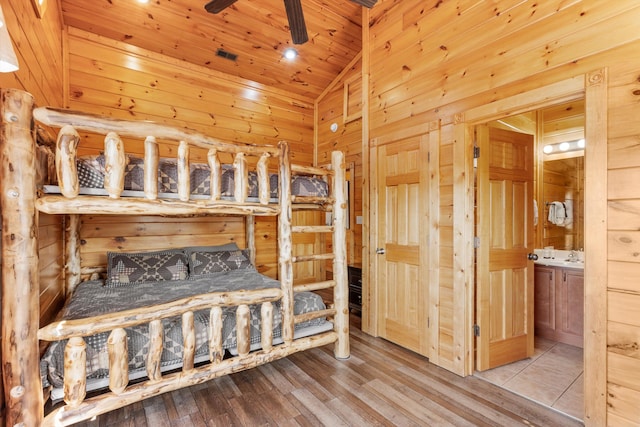 bedroom with wood ceiling, wooden walls, wood finished floors, lofted ceiling, and ensuite bathroom