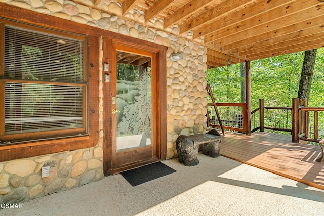 exterior space with carpet flooring and beam ceiling