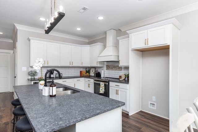 kitchen with premium range hood, white cabinetry, decorative backsplash, electric stove, and sink