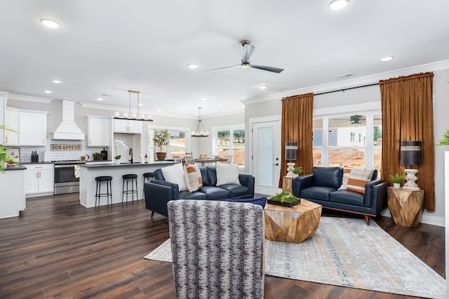 living room featuring dark hardwood / wood-style flooring, ceiling fan with notable chandelier, and crown molding