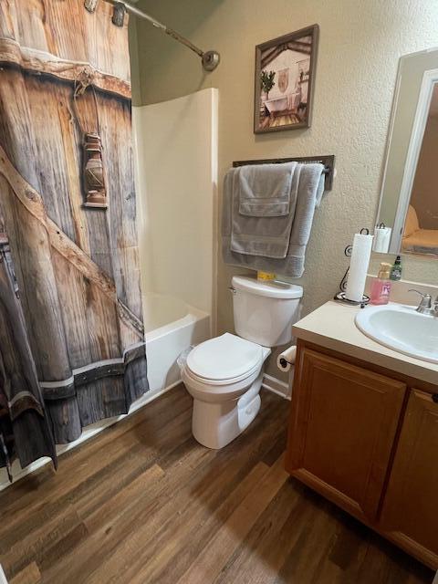 full bathroom featuring vanity, hardwood / wood-style flooring, toilet, and shower / bath combo with shower curtain