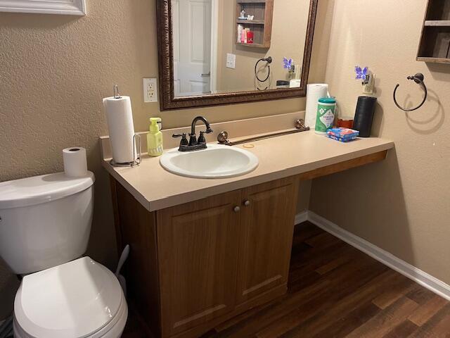 bathroom with hardwood / wood-style floors, vanity, and toilet