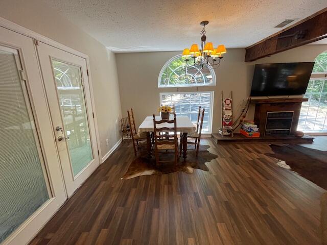 dining area featuring dark wood-type flooring, a textured ceiling, and a chandelier