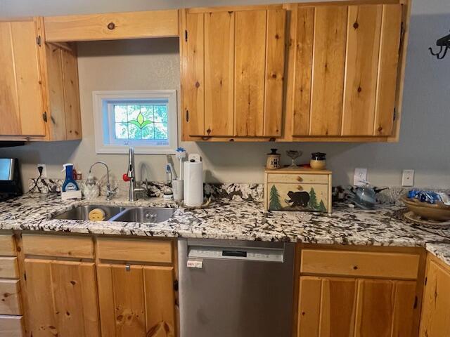 kitchen featuring stainless steel dishwasher, light stone countertops, and sink