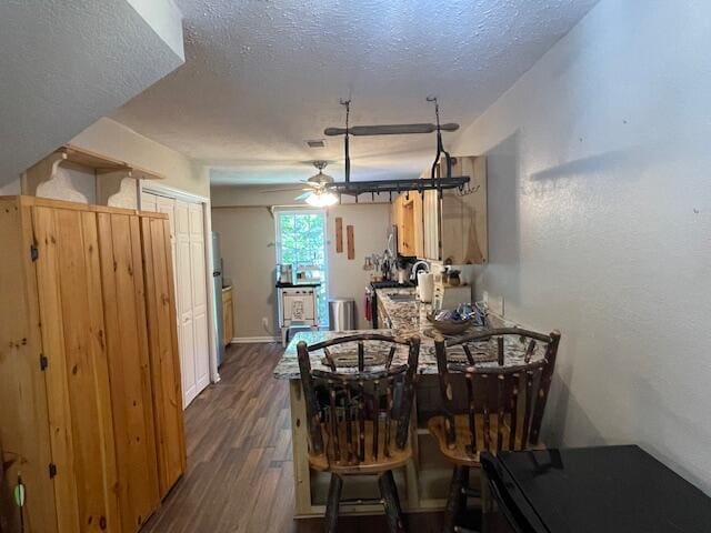 dining room with ceiling fan, a textured ceiling, and dark wood-type flooring