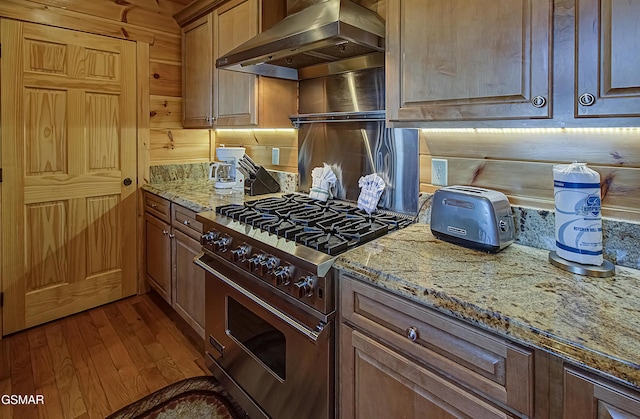 2422 Majestic View Way, Sevierville, TN 37862 - kitchen featuring stainless steel range, wall chimney range hood, dark wood finished floors, light stone countertops, and wooden walls