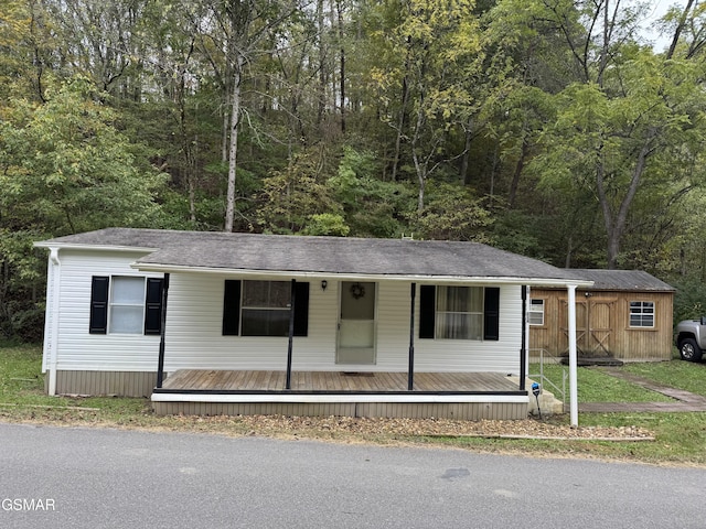 manufactured / mobile home featuring a porch and a view of trees