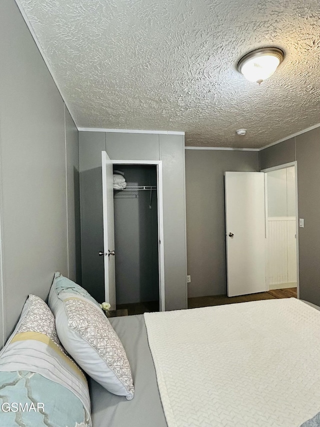 bedroom featuring crown molding, a closet, and a textured ceiling