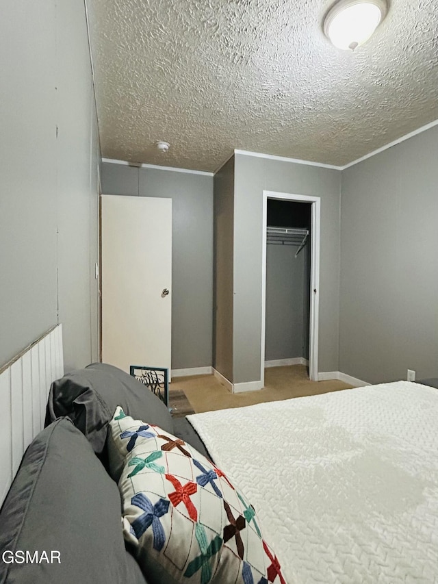 carpeted bedroom featuring a closet, a textured ceiling, baseboards, and ornamental molding