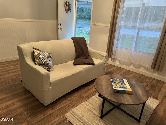 sitting room featuring a wainscoted wall and dark wood-style flooring