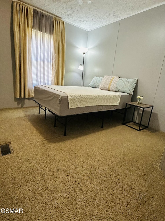 bedroom featuring ornamental molding, visible vents, carpet floors, and a textured ceiling
