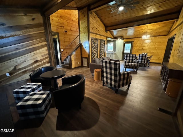 living area with vaulted ceiling with beams, wood walls, stairs, and wooden ceiling