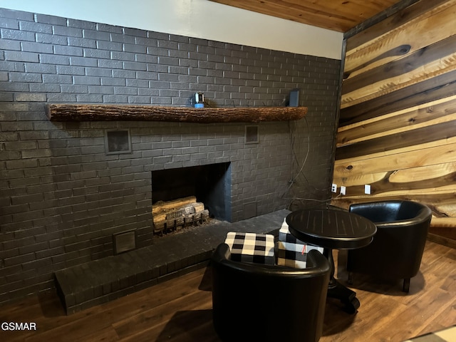 living area with a brick fireplace, wood ceiling, and wood finished floors