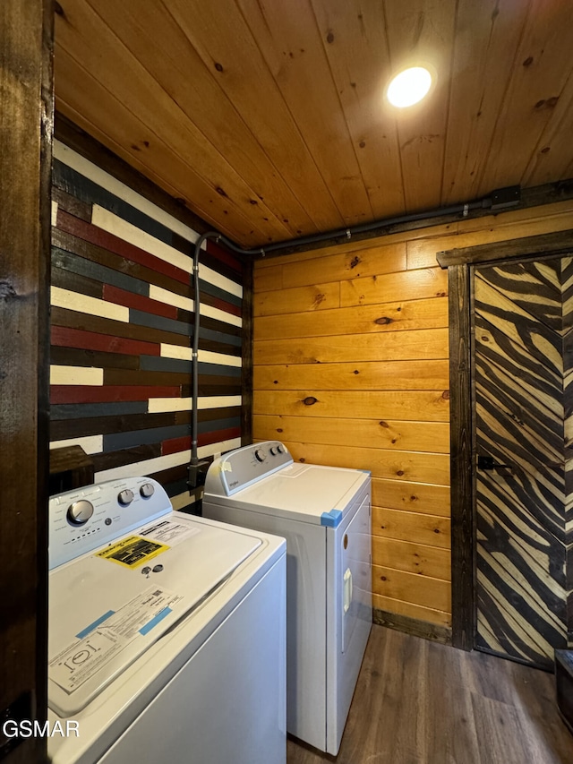 laundry room with dark wood finished floors, washing machine and dryer, wood ceiling, wooden walls, and laundry area