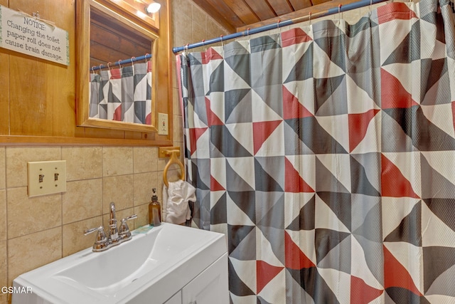 bathroom with a shower with curtain, backsplash, tile walls, and vanity