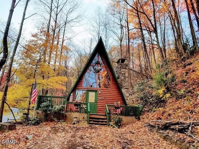 rear view of house with faux log siding and a wooden deck