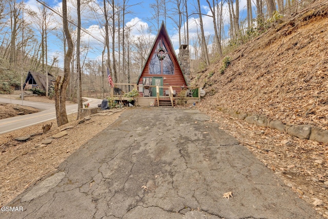 a-frame style home featuring aphalt driveway, a deck, and a chimney