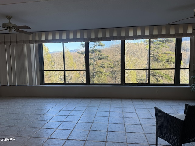 interior space with a forest view and ceiling fan