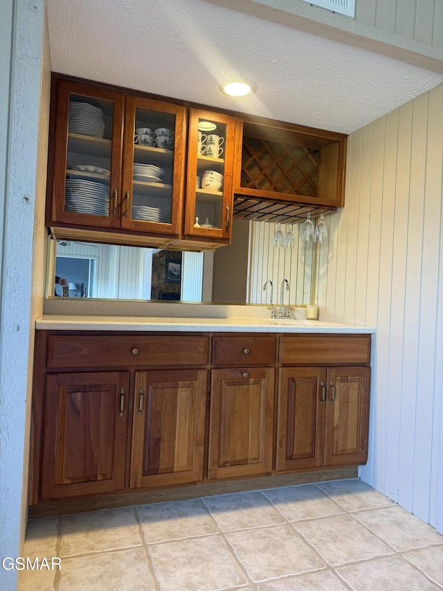 bar with indoor wet bar, a sink, a textured ceiling, and light tile patterned flooring