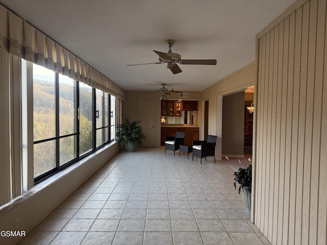 unfurnished sunroom featuring visible vents and ceiling fan