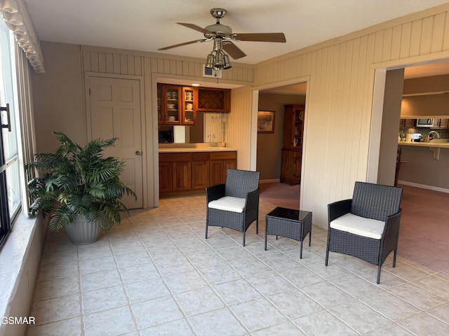 living area featuring crown molding, ceiling fan, and wood walls