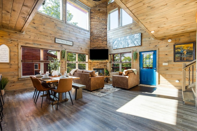 dining room featuring dark wood-type flooring, a stone fireplace, high vaulted ceiling, plenty of natural light, and wood ceiling