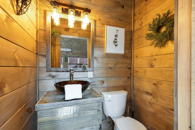 bathroom featuring vanity, toilet, and wooden walls