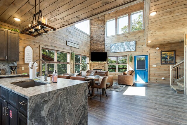 kitchen featuring sink, a high ceiling, light stone counters, decorative light fixtures, and wood ceiling