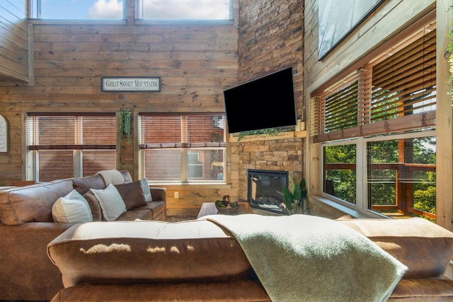 living room with wooden walls, a fireplace, and a towering ceiling