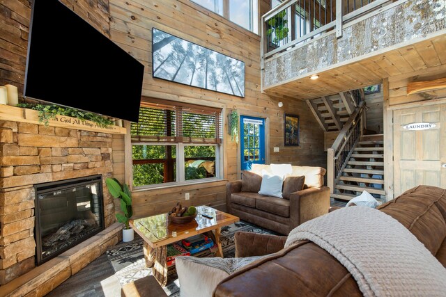 living room featuring wooden walls, a healthy amount of sunlight, a fireplace, and a high ceiling